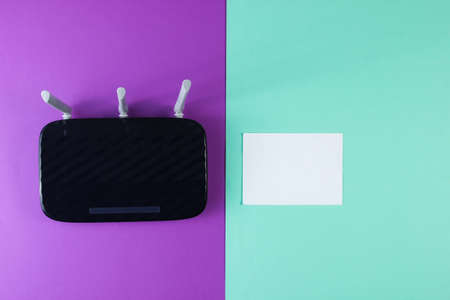 Three antenna wi-fi router with white sheet of paper on purple blue background. Top view