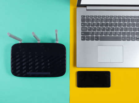Wi fi router, smartphone, laptop on  colored background. Modern gadgets. Top viewの写真素材