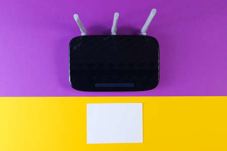Three antenna wi-fi router with white sheet of paper on purple yellow background. Copy space. Top viewの写真素材
