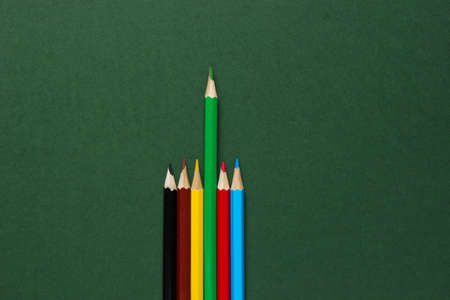 Set of colored pencils on green background. Uniqueness concept.  Top viewの写真素材