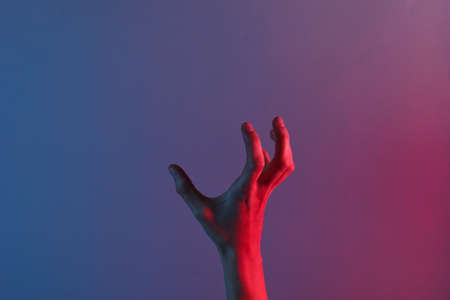 Awesome female hand with blue neon red light. Halloween theme. Minimalism fashion. Surrealism. Concept artの写真素材