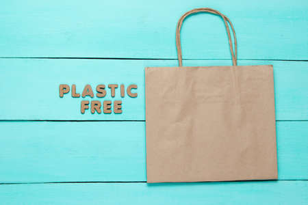 Paper bag on blue wooden background with the words plastic free. Top viewの写真素材