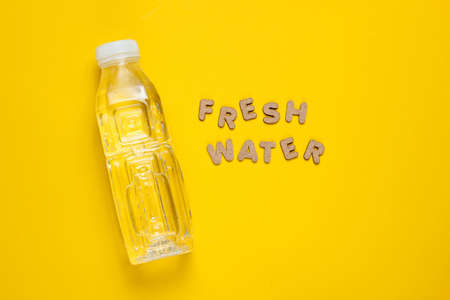 Bottled water on yellow background with the words fresh water.の写真素材