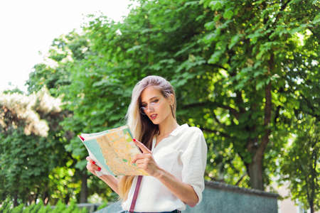 Beautiful woman tourist in casual style clothes using city map while walking around an unfamiliar...