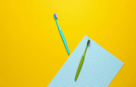 Two new toothbrushes on yellow blue paper background. Minimalism hygiene conceptの写真素材