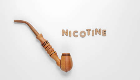 Wooden smoking pipe on white background with word nicotine of  wooden letters