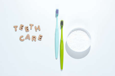 Two toothbrushes, tooth powder on white background with slogan teeth care. Minimalism oral hygiene concept.の写真素材