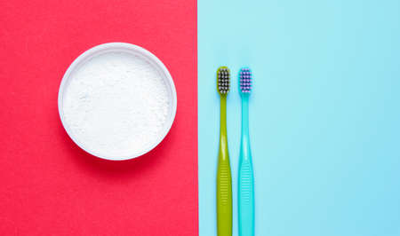 Two toothbrushes, tooth powder on a colored paper background. Minimalism oral hygiene concept. Top viewの写真素材