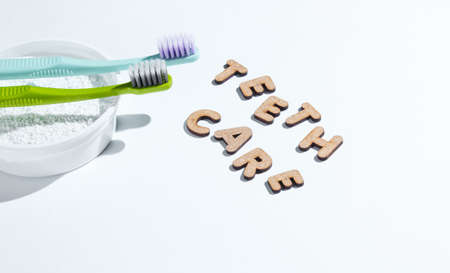 Two toothbrushes, tooth powder on white background with slogan teeth care. Minimalism oral hygiene concept.の写真素材