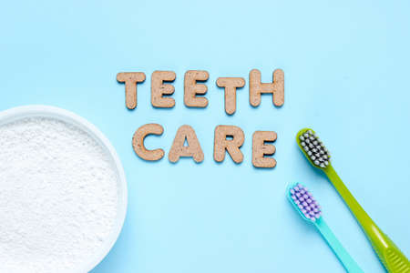 Two toothbrushes, tooth powder on blue background with slogan teeth care. Minimalism oral hygiene concept.の写真素材