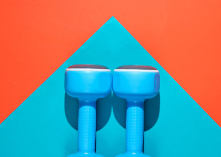 Minimalistic fitness concept. Blue plastic dumbbells on colored paper background. Top viewの写真素材