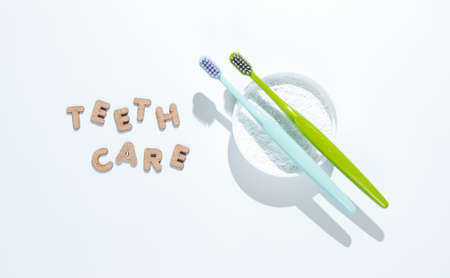 Two toothbrushes, tooth powder on white background with slogan teeth care. Minimalism oral hygiene concept.の写真素材
