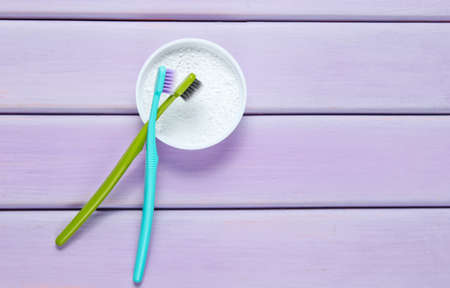 Two toothbrushes, tooth powder on purple wooden background. Minimalism oral hygiene concept. Top viewの写真素材