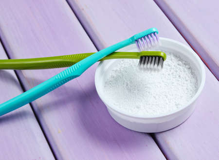 Two toothbrushes, tooth powder on purple wooden background. Minimalism oral hygiene concept. Top viewの写真素材
