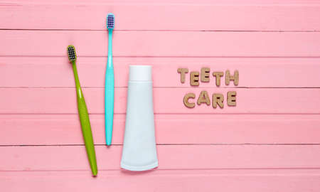 Teeth care concept. Two toothbrushes with a tube of toothpaste on pink wooden background. Top view