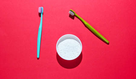 Two toothbrushes, tooth powder on red background. Minimalism oral hygiene concept. Top viewの写真素材