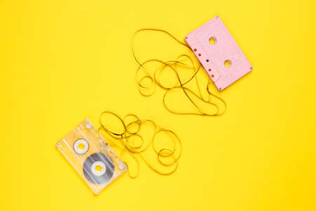 Music lover minimalism concept. Retro style 80s. Two audio cassettes with film on yellow paper background.の写真素材