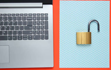 Computer protection concept, internet security. Laptop and lock on orange blue paper background