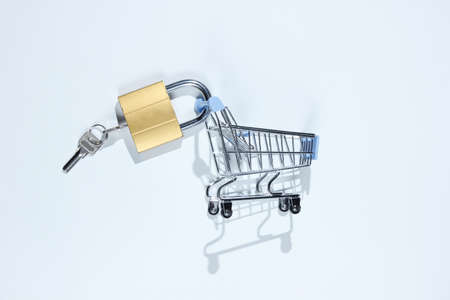 Minimalistic shopping concept. Mini shopping trolley with a lock on white background. Top viewの写真素材