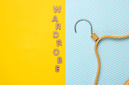 Wooden hanger on a yellow blue background with the word wardrobe. Top viewの写真素材