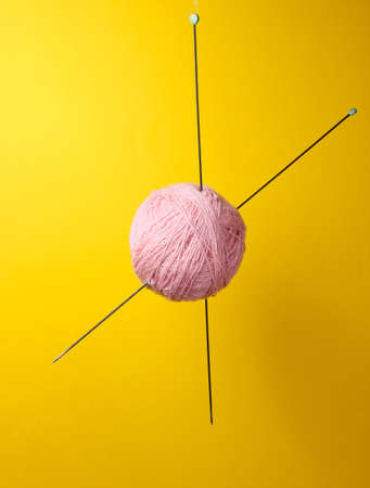 Home hobbies concept. Wool balls of thread with knitting needles on yellow background.の写真素材