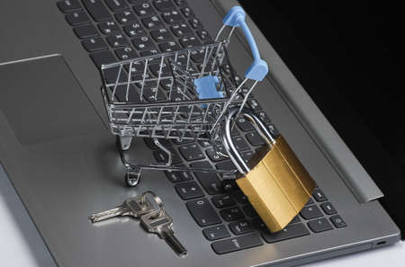 Restriction on online shopping minimalistic concept. Mini shopping trolley with lock on laptop keyboardの写真素材