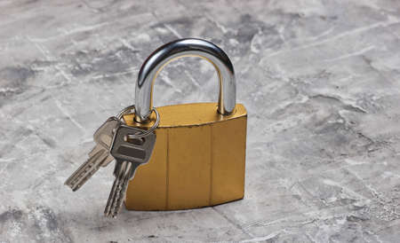 Metal lock with keys on gray concrete background.の写真素材