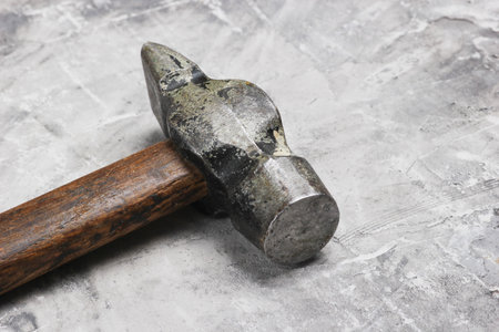 Old hammer on gray concrete background close up