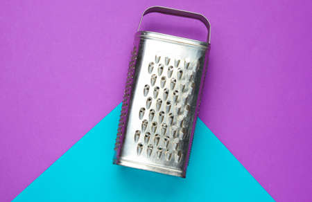 Metal grater on a blue-purple background. Minimalistic food concept. Top viewの写真素材