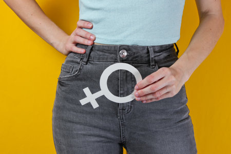 Femen concept. Woman holds in her hands gender feminism symbol on yellow background. Crop photo, studio shotの写真素材