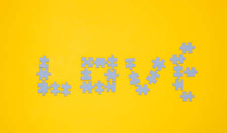 Particles puzzle in the shape of the word love on a yellow backgroundの写真素材