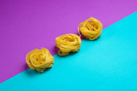 Minimalism italian food concept. Raw tagliatelle noodles on a blue-purple backgroundの写真素材