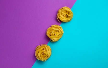 Minimalism italian food concept. Raw tagliatelle noodles on a blue-purple backgroundの写真素材