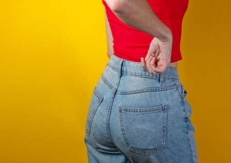 Woman in blue jeans on a yellow background. Back view. Studio shotの写真素材