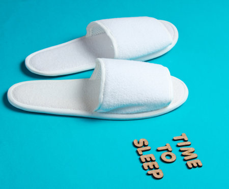 Time to sleep. White sleeping hotel slippers on a blue backgroundの写真素材