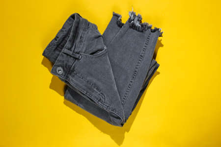 Minimalism fashion concept. Gray trend jeans on a yellow background