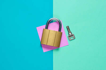 Lock with key on a colored paper background. Top view