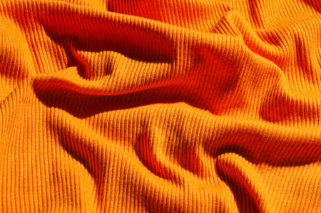 Background of crumpled orange fabric texture closeup.の写真素材
