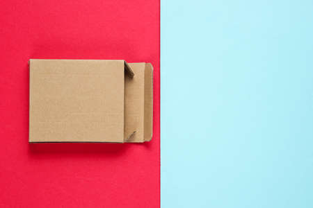 Empty cardboard box on color paper background. Top view