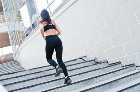 Attractive woman running up on stairs outdoors. Back view