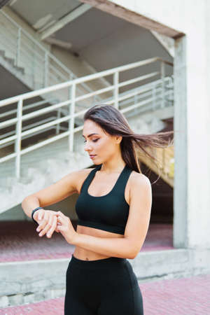 Attractive sport woman in sportswear use smart watch outdoors at urban environmentの写真素材