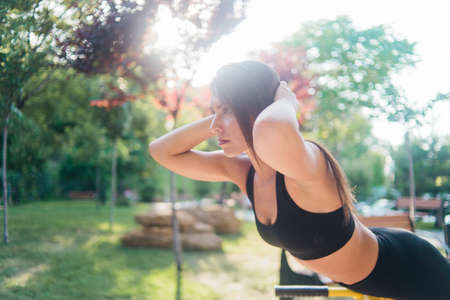 Healthy fit woman in sport clothes doing exercise on outdoors exercise machineの写真素材
