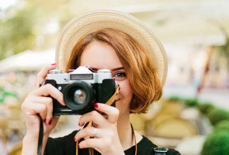 Smilling hipster woman holding a retro camera in her hands and taking a pictureの写真素材