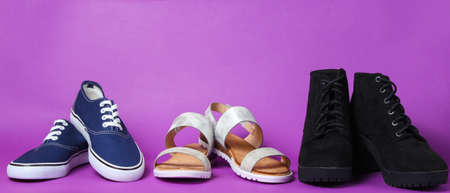 Variety of seasonal shoes. Sandals, boots, sneakers on purple background.の写真素材