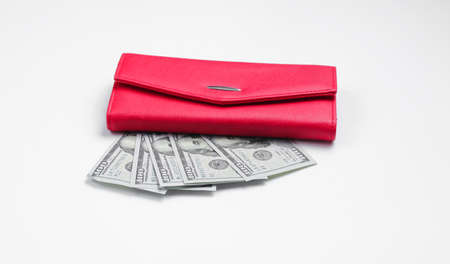 Red purse and hundred dollar bills on a white background. Minimalistic financial concept of family budgetの写真素材