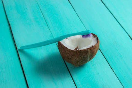The concept of eco-friendly products for dental care. Toothbrush and half coconut on a blue wooden backgroundの写真素材