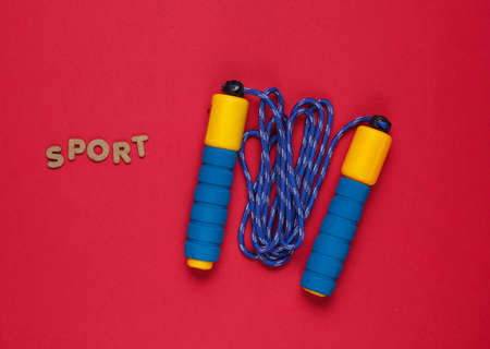 Minimalism fitness concept. Word sport. Skipping rope on purple yellow background. Top view