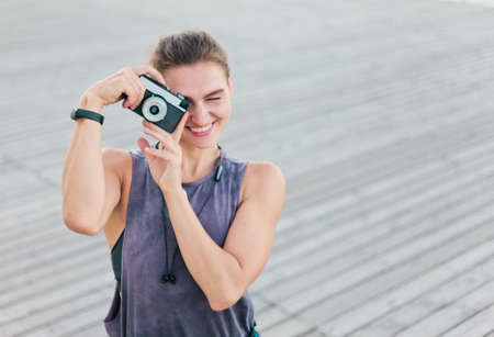 Young attractive sport woman outdoors taking pictures on retro cameraの写真素材