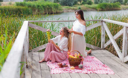 Two cheerful young women have a picnic outdoors on a summer day. Two girlfriends in retro vintage...