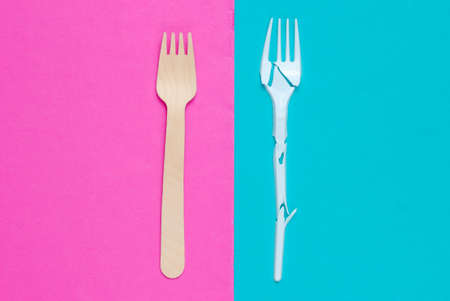 Minimalistic ecologically clean still life. Pop Art. Broken plastic fork and wooden fork on blue pink background. Cutlery made from natural materials, Top viewの写真素材